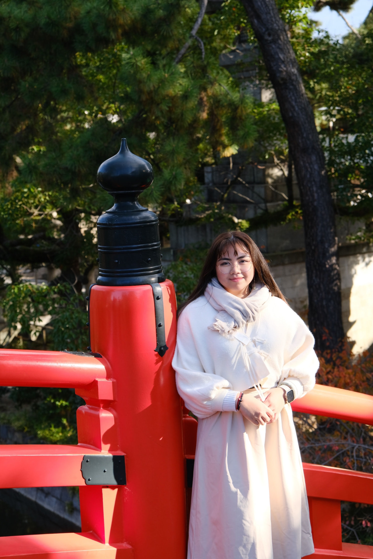 Sam standing beside a bright red bridge in Japan
